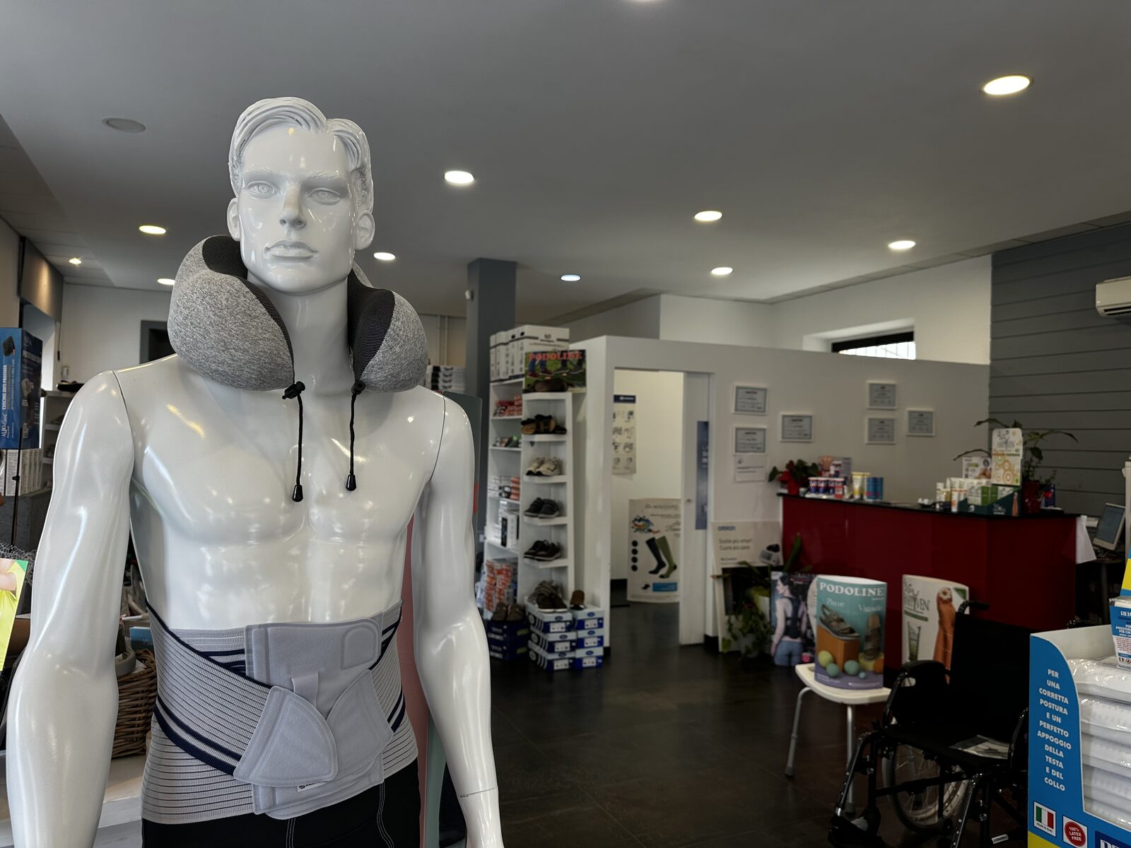 Manichino con busto ortopedico e cuscino cervicale all'interno del negozio